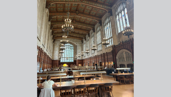 Student studying in a large historic reading room at the University of Michigan.